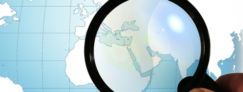 Lupe über einer Weltkarte, die den Nahen Osten unter der Linse hat