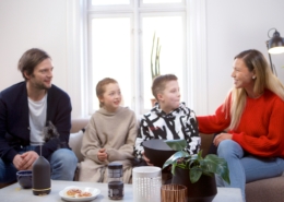 Eine Frau und ein Mann mit zwei Kindern sitzen auf einem Sofa