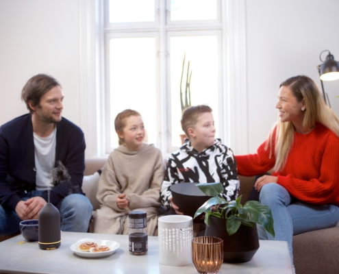 Eine Frau und ein Mann mit zwei Kindern sitzen auf einem Sofa