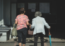 Zwei Damen, die spazieren gehen, dabei hilft die jüngere Dame der Älteren