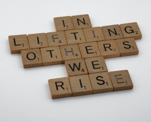 Buchstaben auf Holz, Text: in lifting others we rise