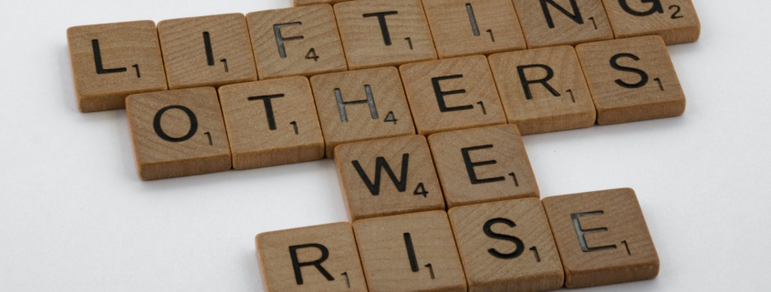 Buchstaben auf Holz, Text: in lifting others we rise