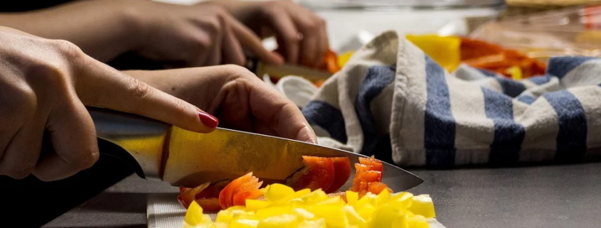 Frauenhände, die Gemüse schneiden